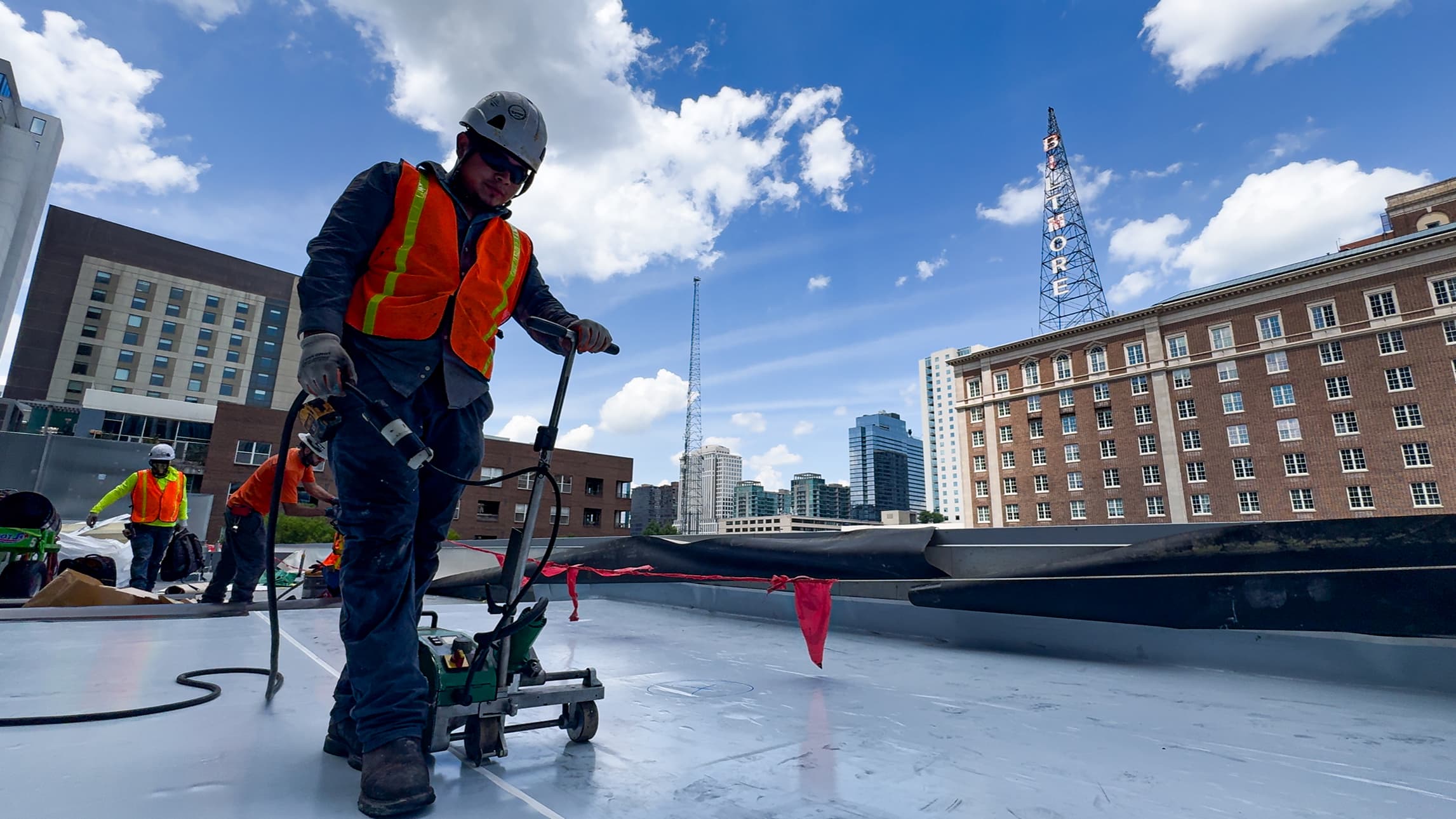 commercial roofer guiding a heating machine